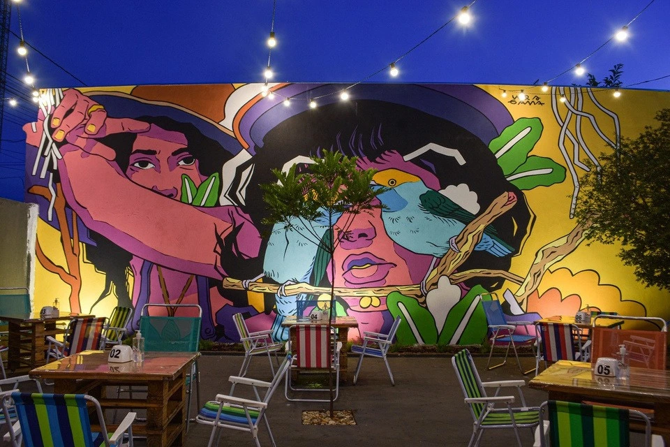 Pátio real da Casa Velha, com mesas, cadeiras e mural colorido